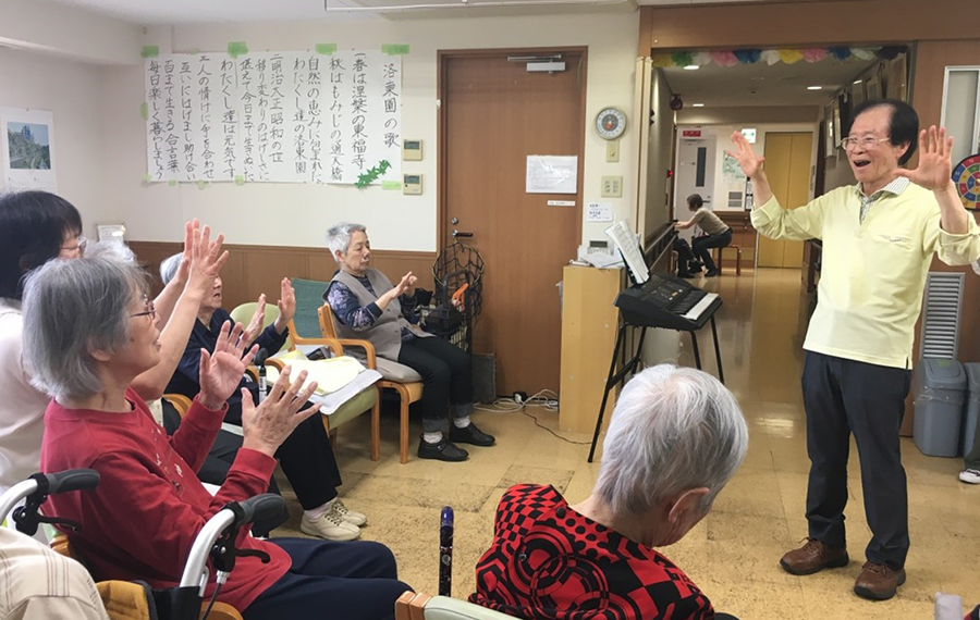 高齢者福祉施設での音楽ボランティア活動。ボランティア会員が歌に合わせて手遊（あそ）びや体操をしています。